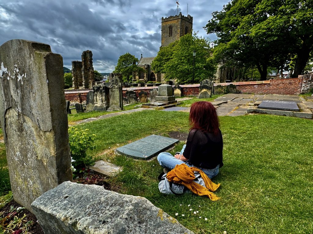 Aparezco sentada junto a la tumba de Anne Bronte